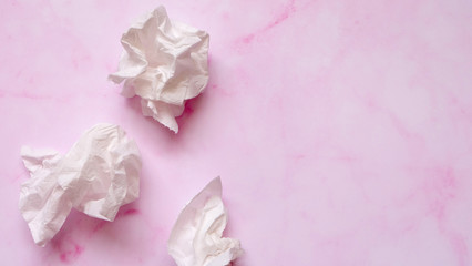 White crumpled tissue paper on a pink marble background.