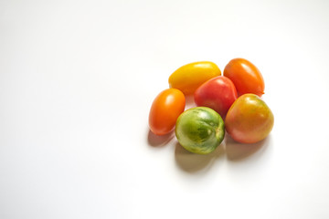 Heap of multicolored tomatoes on white background with copy space