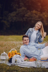 beautiful long-haired blonde with her handsome man sitting in the park with fruits