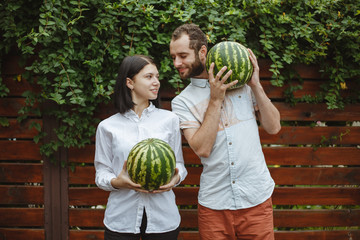 Fototapeta premium Portrait of a smiling couple with a watermelon in their hands. Wooden background.