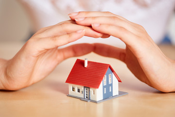 Hands protect house as insurance concept