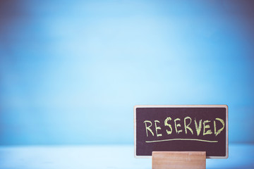 reserved text on wooden blackboard on table over blue wall background.