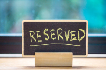 reserved text on wooden blackboard on wooden table.