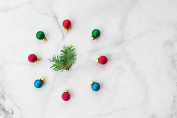 Stylized Christmas clock made of fir-tree branch with blue and red ball toys on marble background. New Year and Christmas celebration concept. Flat lay, top view.