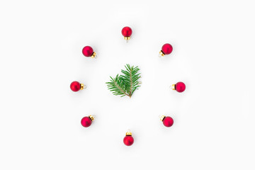Stylized Christmas clock made of fir-tree branch with red ball toys on white background. New Year and Christmas celebration concept. Flat lay, top view.