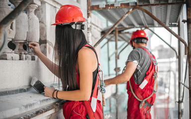 Two workers standing on scaffolding and restore old building facade