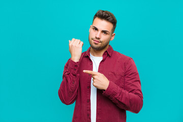 young hispanic man looking impatient and angry, pointing at watch, asking for punctuality, wants to...