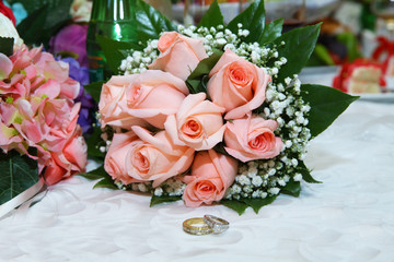 Gold wedding rings on the pink bouquet of flowers . Stylish pink engagement flower Rings in front of the wedding bouquet .