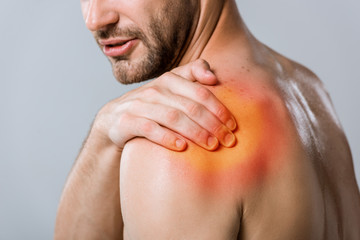 cropped view of shirtless sportsman with shoulder pain isolated on grey