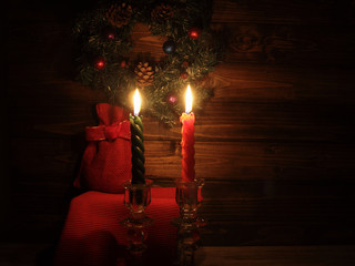Candles and Santa bag with Christmas decorations in dark interior