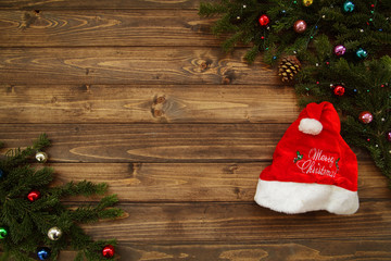 Fir tree branches with Christmas decoration and Santa cap against old vintage style wooden planks. Christmas/New Year concept. Christmas card theme.