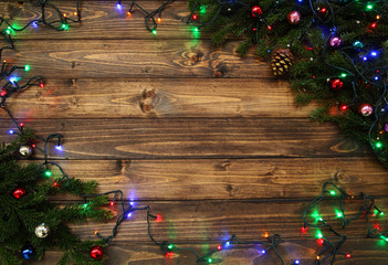 Fir tree branches with Christmas decoration and twinkle lights against old vintage style wooden planks. Christmas/New Year concept. Christmas card theme.
