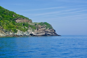 Greened cliff ending in the blue ocean