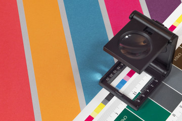 Black magnifying  glass standing on  the test print with colored background. Print loupe on offset...