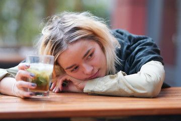 Attractive woman in her 20s with a glass cocktail or ice tea outside in sunlight