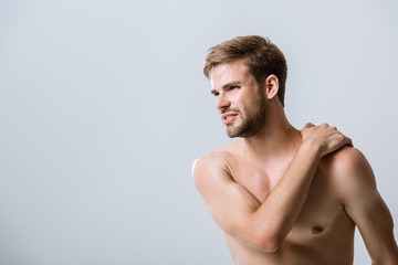 Fototapeta premium shirtless bearded man with pain in shoulder isolated on grey