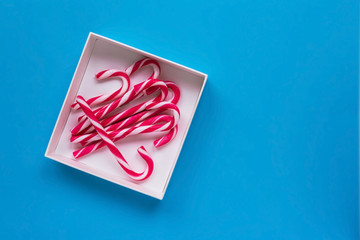 Some lollipop cane in a white box on a blue background. The xmas concept
