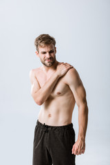 Naklejka premium shirtless bearded sportsman with pain in shoulder isolated on grey