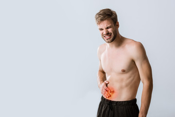 Fototapeta na wymiar shirtless sportman with abdominal pain isolated on grey