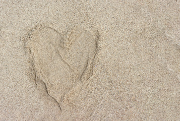 Heart shape by human foot print on sand beach.