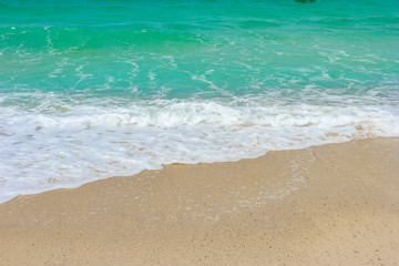 Fototapeta na wymiar Natural splashing wave sea on sand beach on sunny day at island.