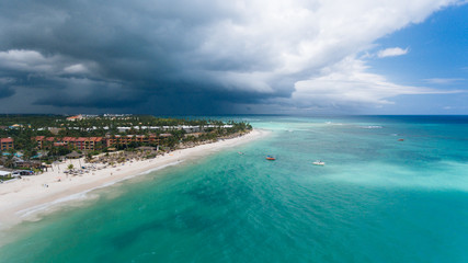 stunning panorama of the blue sea and yellow sand with palm trees, beautiful green palm trees on the shore, aerial view from a flying drone, shooting from a copter, Punta Cana, Dominican Republic