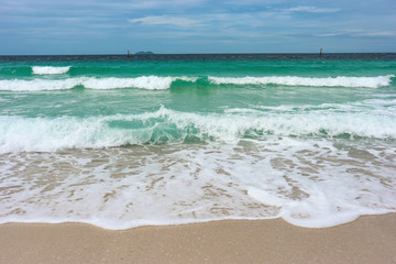 Natural splashing wave sea on sand beach on sunny day at island.