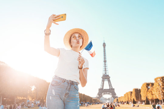 Happy Asian girl taking selfie photo on her smartphone on the background of the Eiffel tower. Travel and image quality concept
