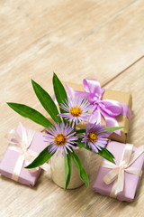 Plakat Purple spring flowers in a white vase on a wooden table. Gift box wrapped in craft paper with ribbon