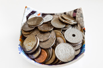 Collection of Ukrain, Switzerland and Norway coins in a bowl on white background
