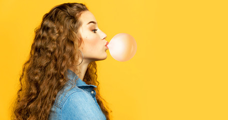Portrait of funny young model chewing bubblegum. Attractive woman posing in profile in studio on...