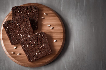 Sliced bread with sunflower seeds on cutting Board on dark background.