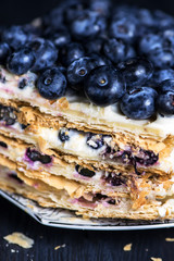 puff pastry cake with white cream and berry, blueberries on a dark background