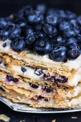 puff pastry cake with white cream and berry, blueberries on a dark background