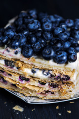 puff pastry cake with white cream and berry, blueberries on a dark background