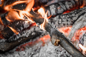 Burnt firewood in a fire turned into red coals and ashes. Preparing a campfire for cooking on charcoal.