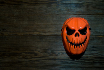 Orange devil mask placed on an old wooden plate at night, Focus on the mask, Copy-space