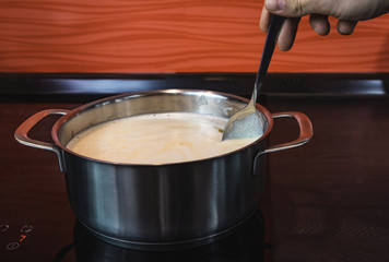 Clarification of butter, clarified butter in a steel pot mixed with steel spoon. Removing foam from butter.