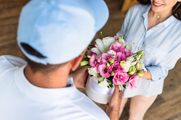 overhead view of delivery man giving flowers to cheerful woman