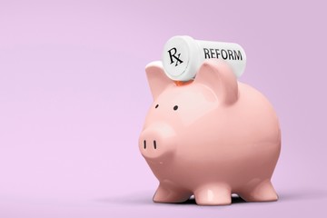 Hand putting coin to piggy bank on blue background