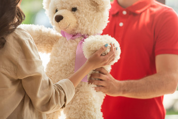 cropped view of girl receiving teddy bear from man