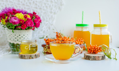 White background, natural lighting. Warm sweet organic tea with sea buckthorn berries, thyme and honey.