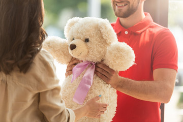 cropped view of happy bearded man giving teddy bear to woman