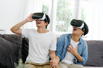 Young asian men, gay couple playing VR with happiness at home living room, Asia boys wearing VR glasses to play virtual simulator, Homosexual, lgbt couple lifestyle