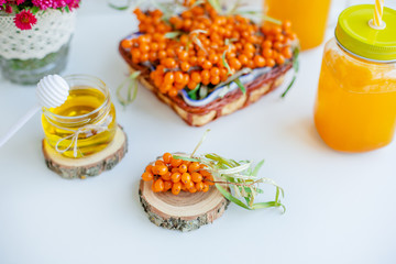 White background, natural lighting. Warm sweet organic tea with sea buckthorn berries, thyme and honey.