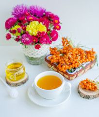 White background, natural lighting. Warm sweet organic tea with sea buckthorn berries, thyme and honey.