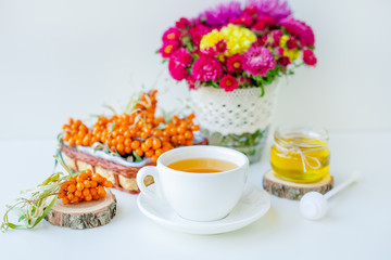 Obraz na płótnie Canvas White background, natural lighting. Warm sweet organic tea with sea buckthorn berries, thyme and honey.