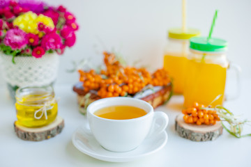White background, natural lighting. Warm sweet organic tea with sea buckthorn berries, thyme and honey.