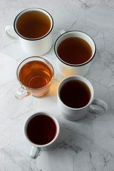 Top view of various cups, mugs with hot tea drink on light background, copy space. Tea time or tea brake. Autumn beverage. Toned image with tea cups.