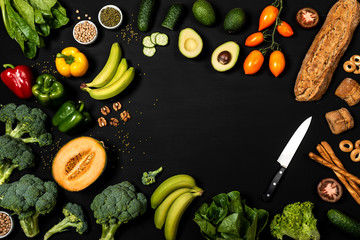 Frame of different vegetables and bread products on a black background with place for text. Balanced diet or cooking concept. Healthy vegan food. Top view.